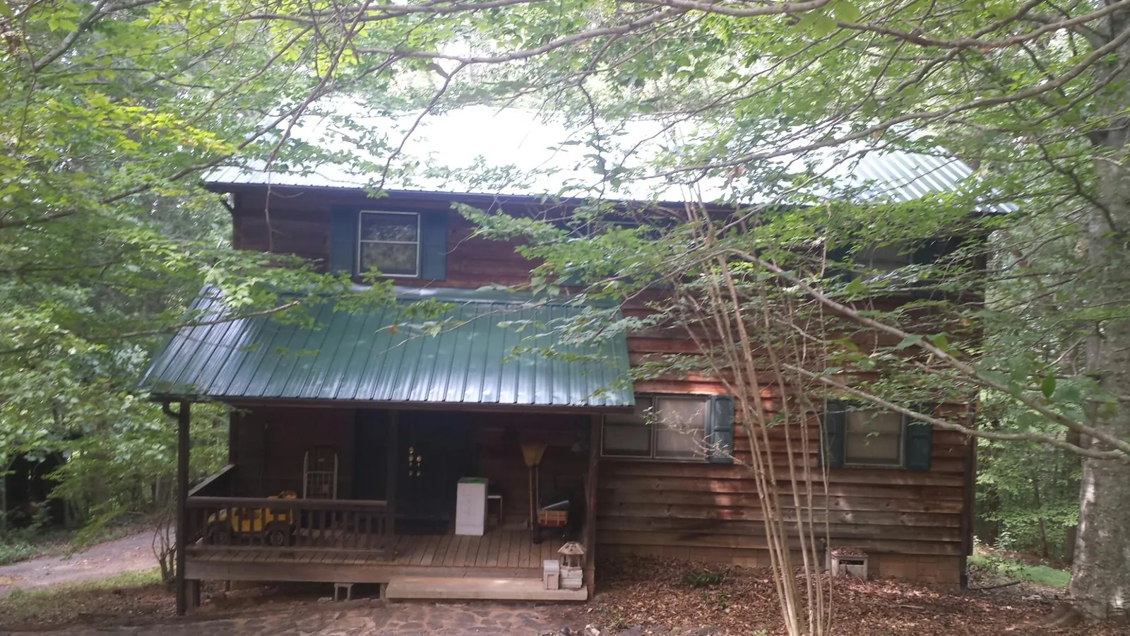 Green metal roof and covered porch on a log cabin in Mantua
