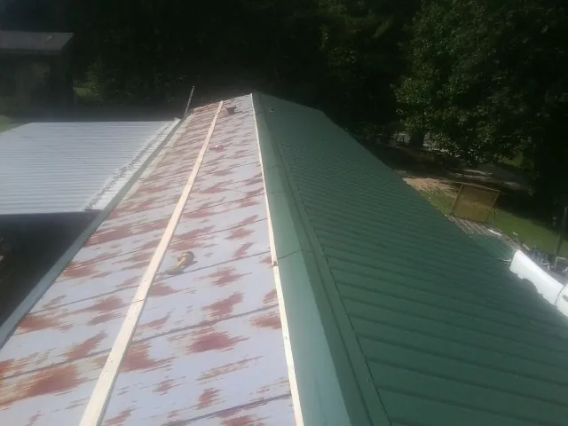 Old rusted panels beside newly installed green metal roofing — Wind Damage Roof Repair by Roofing Brothers in Mantua