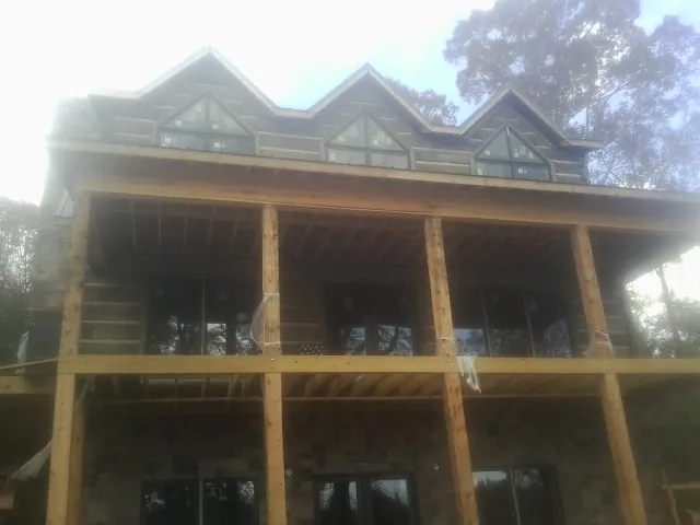 Dormers and porch framing on a large log home under construction — Roof Coating work by our crew in Mantua