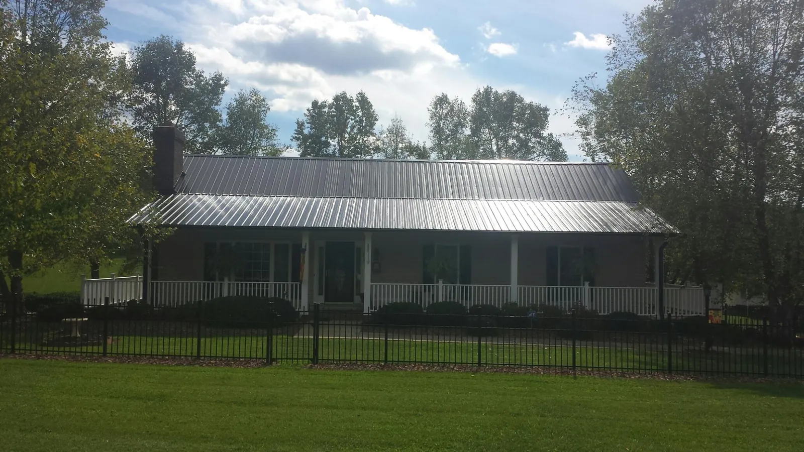 Gray metal roof on a brick ranch with a full width front porch — Gutter Guard Installation work by our crew in Mantua